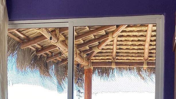 Una habitación con puerta corrediza de vidrio que da a un balcón con vista al océano.