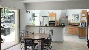 Une cuisine moderne avec un coin repas, comprenant un îlot central, des meubles en bois et une grande fenêtre.