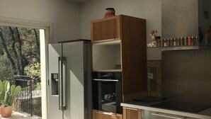 Une cuisine moderne dotée d’un réfrigérateur encastré, de meubles en bois et d’une grande fenêtre offrant une vue sur l’extérieur.