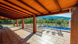 Un espace extérieur abrité comprenant une piscine, des chaises longues et une vue sur les montagnes.