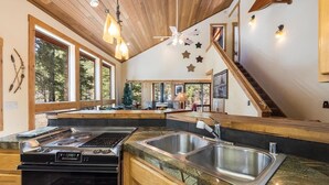 Une cuisine moderne équipée d’une cuisinière à gaz, d’un évier double et de plans de travail en bois.