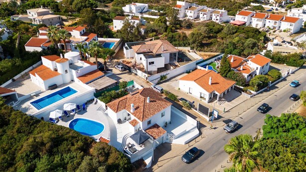 Una zona residencial costera con edificios blancos, una piscina y una calle con automóviles.