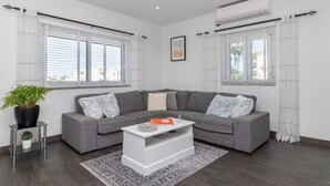 Una sala de estar moderna con un sofá seccional gris, una mesa de centro blanca y una planta en maceta.