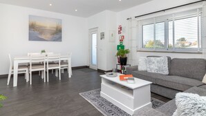 Una sala de estar moderna con comedor, un sofá, una mesa de centro y un cuadro en la pared.