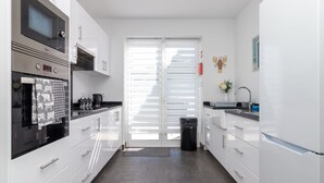 Una cocina moderna con gabinetes blancos, electrodomésticos de acero inoxidable y un cubo de basura negro.