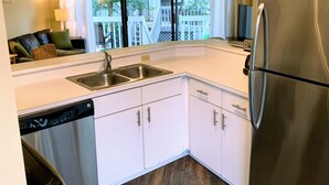Una cocina moderna con armarios blancos, electrodomésticos de acero inoxidable y vistas al exterior.