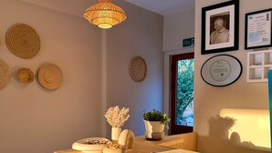 A reception area with a wooden counter, decorative woven wall hangings, a hanging light fixture, framed certificates, and a window with a view of greenery. - Cennet Hotel (Fethiye)