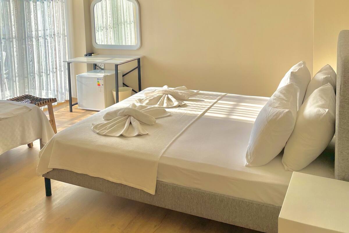 A neatly arranged bedroom with a bed, bedside table, and a small desk with a mirror.