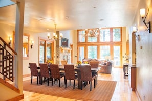Uma sala de jantar espaçosa com uma mesa grande e cadeiras, lareira e um candelabro.