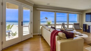 Amplia sala de estar con un gran ventanal corredizo que da a un balcón con vista a la playa.