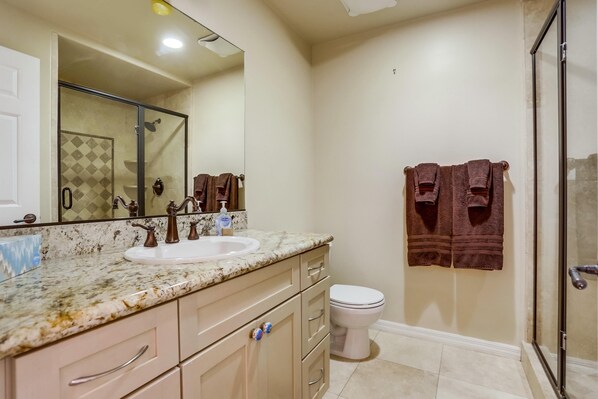 Een badkamer met een wastafel, spiegel, toilet en douche.