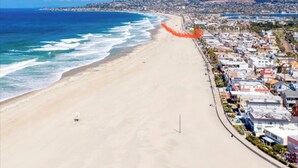 Un paisaje urbano costero con una playa extensa, edificios residenciales y un cielo azul despejado.