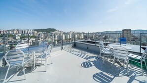 A rooftop terrace with metal chairs and tables, offering a panoramic city view. - Hotel RU136 (Seoul)