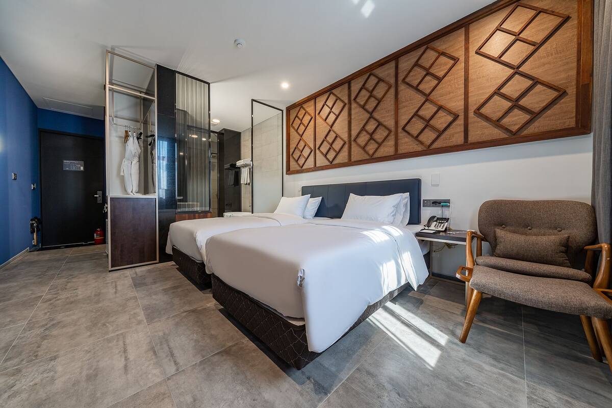 A modern hotel room with a large bed, a seating area, and a bathroom with a glass shower enclosure.