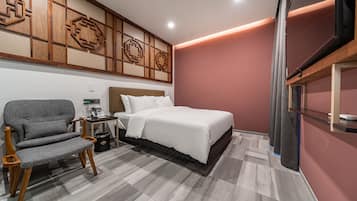 A modern bedroom with a bed, a grey upholstered chair, and a wooden headboard.