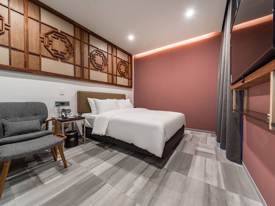 A modern bedroom with a bed, a grey upholstered chair, and a wooden headboard.