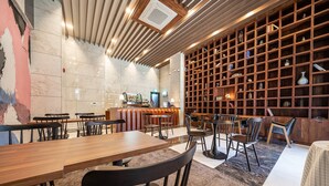 A modern restaurant with wooden tables and chairs, a bar area, and a large bookshelf filled with books and decorative items. - Hotel RU136 (Seoul)