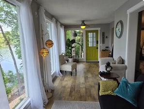 Una habitación con vistas a un lago, una puerta verde, un ventilador de techo y un reloj en la pared.
