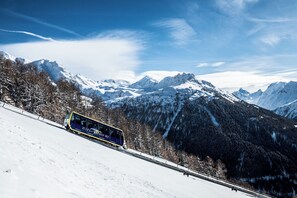 A train on a snowy mountain track with snow-covered mountains in the background.