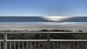 Vista da praia a partir de uma varanda com guarda-corpo.