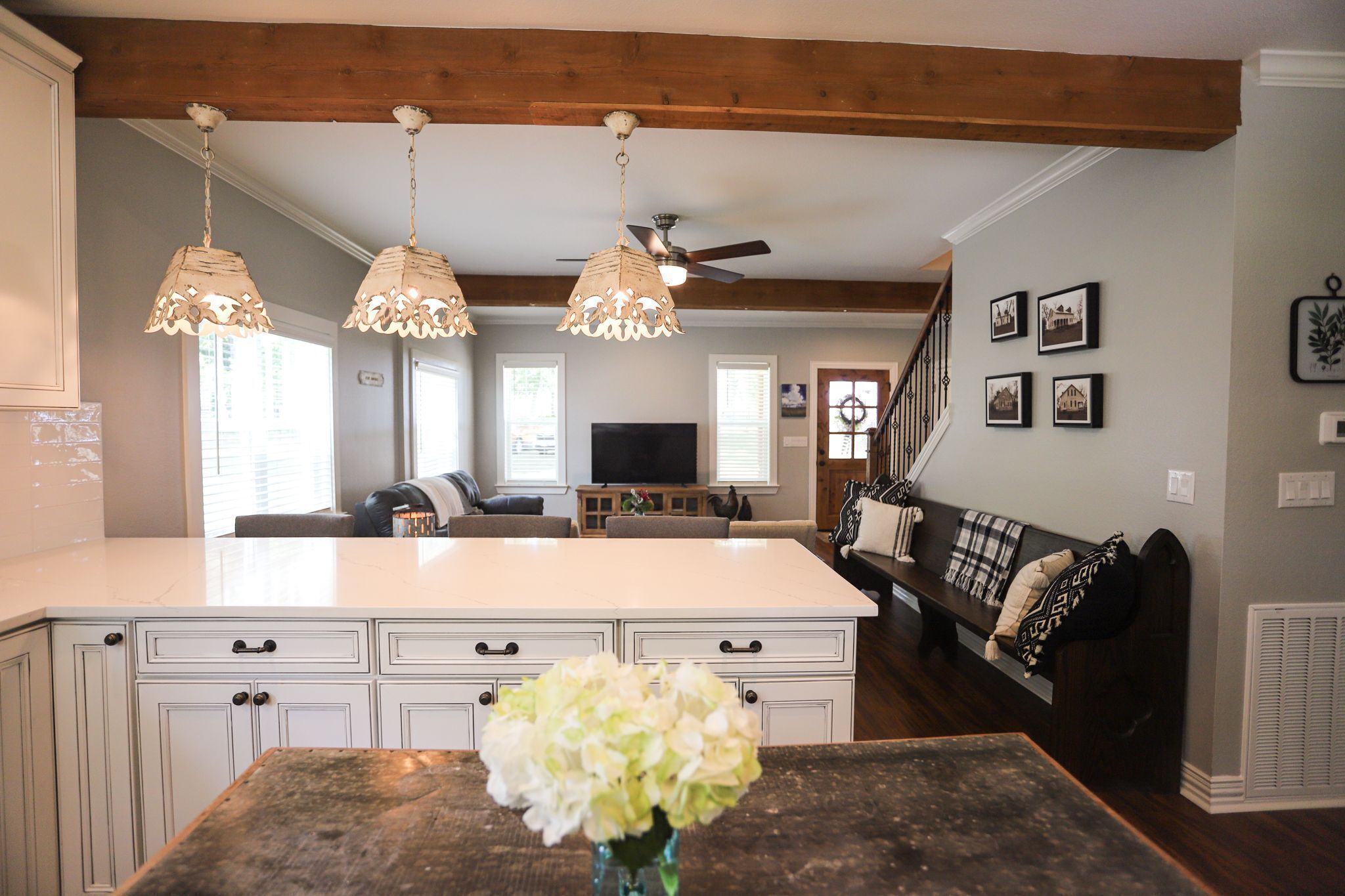 A spacious kitchen with white cabinetry, a central island, and hanging pendant lights.