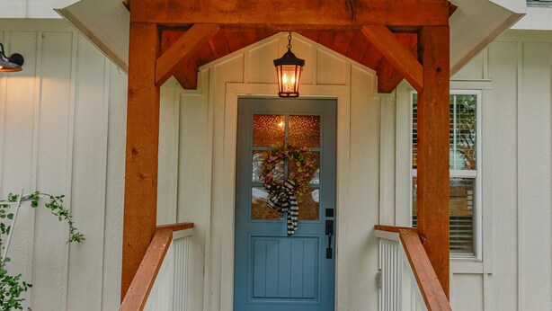 Una casa con una porta blu, un portico in legno e dei gradini in mattoni.