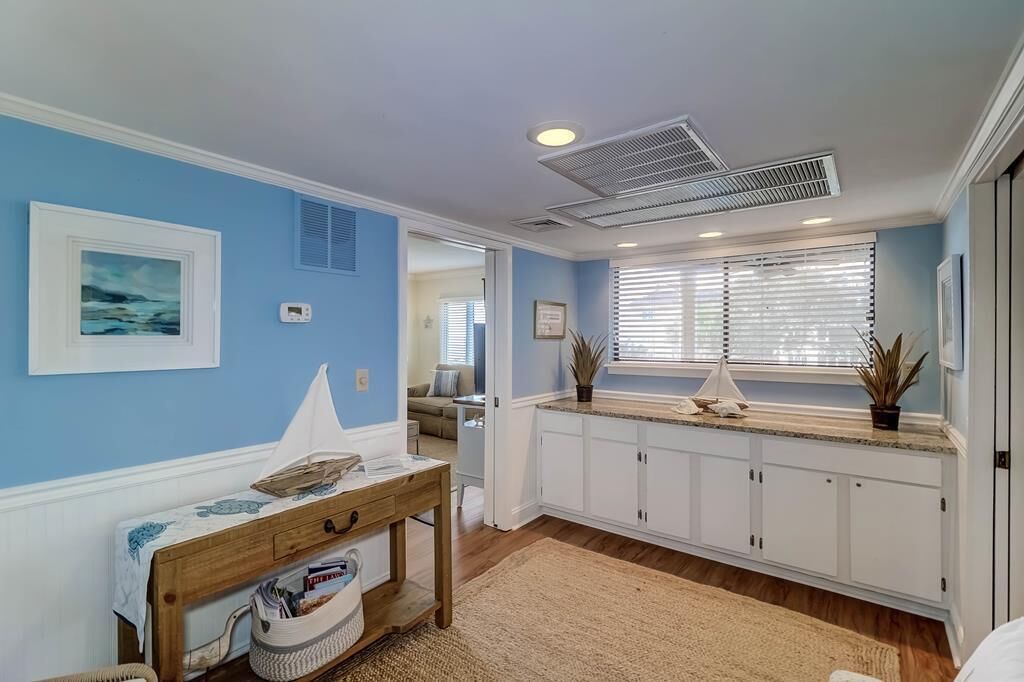 A kitchen with white cabinets, a wooden table, and a window with blinds.