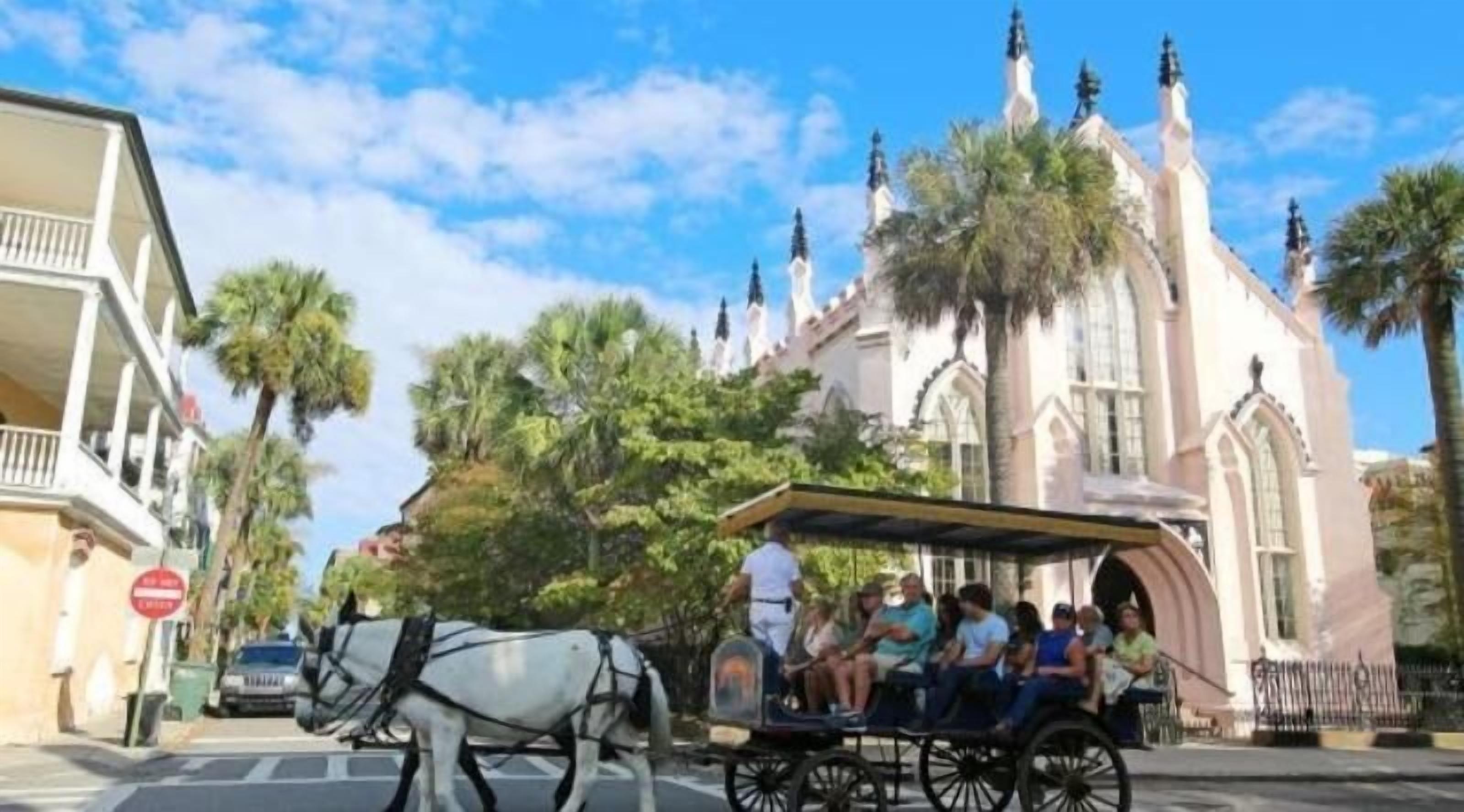 A horse-drawn carriage with passengers, a church with spires, and palm trees.