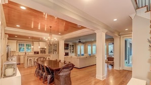 A spacious kitchen with wooden floors, a dining area with wicker chairs, and a large island. - 2602 Hartnett Boulevard (Isle of Palms)
