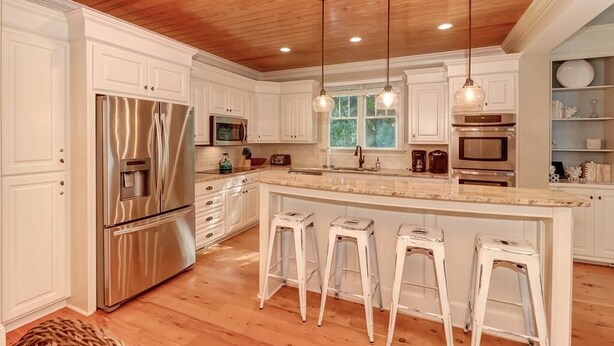 A modern kitchen with white cabinetry, stainless steel appliances, and a wooden ceiling. - 2602 Hartnett Boulevard (Isle of Palms)