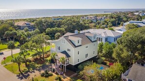 A large two-story house with a balcony, surrounded by lush greenery and a view of the ocean. - 2307 Palm Boulevard (Isle of Palms)