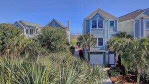 A row of coastal houses with a clear view of the ocean, surrounded by lush greenery and palm trees. - 21 Ocean Point (Isle of Palms)