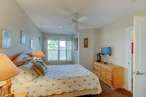 A bedroom with a bed, bedside lamps, a television, a dresser, and a ceiling fan. - 1010 Ocean Palms 201 (Isle of Palms)