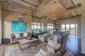A spacious living area with a high ceiling, a large painting, and a dining area with a kitchen in the background. - 305 Carolina Boulevard (Isle of Palms)