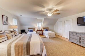 A bedroom with two beds, a ceiling fan, a TV, and a dresser.