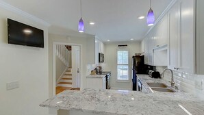 A modern kitchen with white cabinets, a marble countertop, and pendant lighting. - 50 Fairway Dunes (Isle of Palms)
