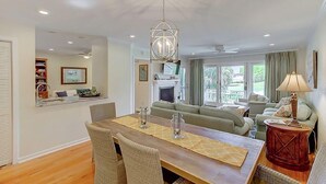 A spacious living area with a wooden dining table, wicker chairs, a sofa set, and a fireplace. - 50 Fairway Dunes (Isle of Palms)