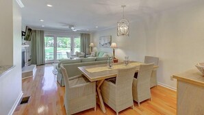 A spacious living area with a dining table, wicker chairs, and a chandelier. - 50 Fairway Dunes (Isle of Palms)
