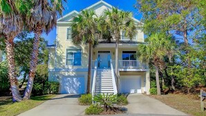 A two-story house with a front porch, a garage, and a staircase leading to the entrance.
