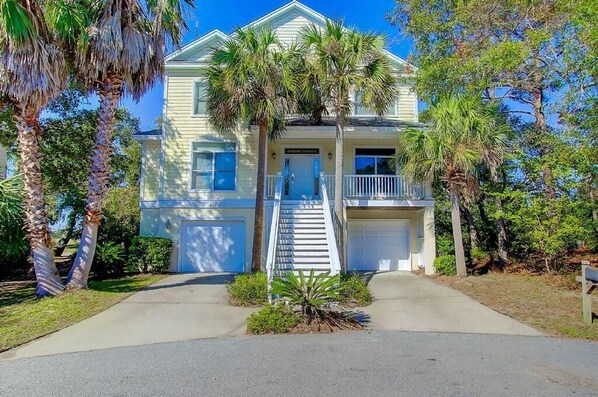 A two-story house with a front porch, a garage, and a staircase leading to the entrance.
