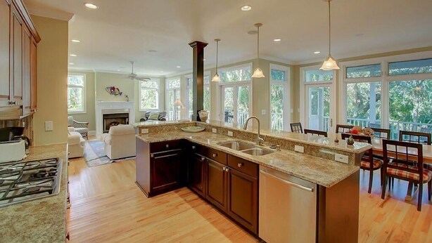 A spacious kitchen with a large island, dark cabinetry, and pendant lighting.