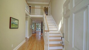 A spacious hallway with a wooden staircase leading to an upper level.