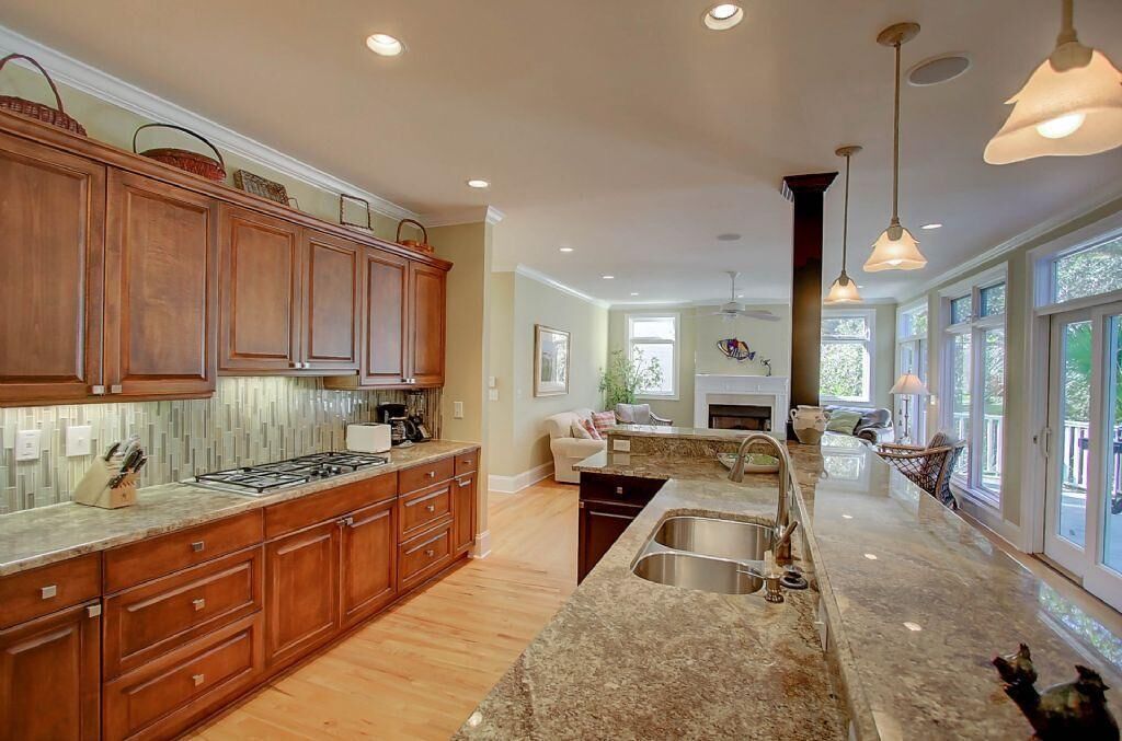 A spacious kitchen with wooden cabinets, granite countertops, and a large island with a sink.