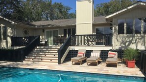 Une piscine dotée de chaises longues et d’un escalier menant à une terrasse.