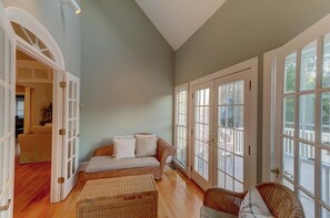 A spacious room with a high ceiling, large windows, and a cozy seating area with a sofa and chairs. - 17 56th Avenue (Isle of Palms)