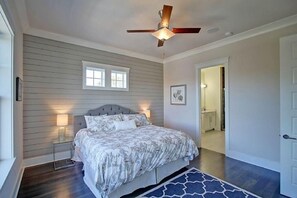 A bedroom with a bed, bedside lamps, a ceiling fan, and a window.