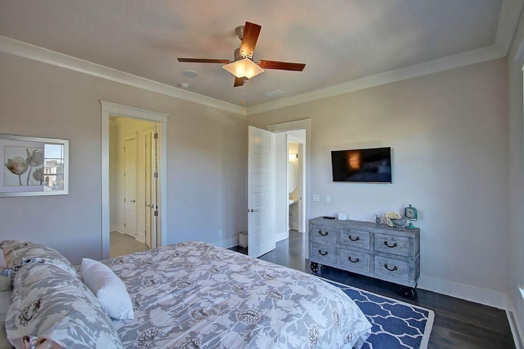 Une chambre à coucher comprenant un lit, une commode, un ventilateur de plafond et un téléviseur.