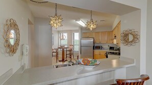 A modern kitchen with a central island, wooden cabinets, and pendant lighting.