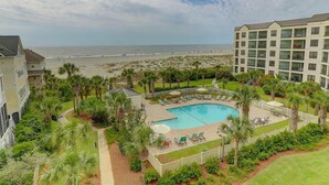 A resort with a swimming pool, palm trees, and a view of the beach.