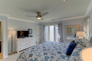 A bedroom with a bed, dresser, television, ceiling fan, and a window with curtains. - 52 Fairway Dunes (Isle of Palms)